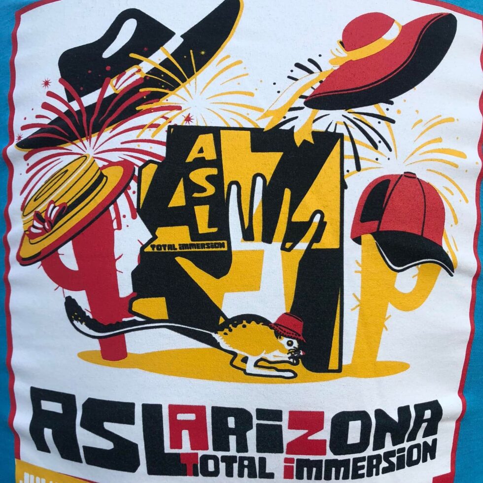 Back of the shirt– white rectangle against blue backgroud. Inside the rectangle are designs of a cowboy hat, cap, sun hat, a open-palm hand, a kangaroo, and text "ASL Arizona Total Immersion 2022". Theme colors are yellow, red and black.